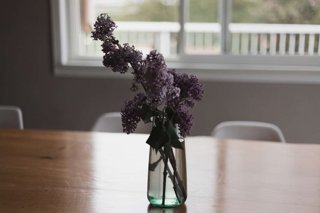 Flores de color púrpura en florero de vidrio verde en la mesa rompecabezas en línea