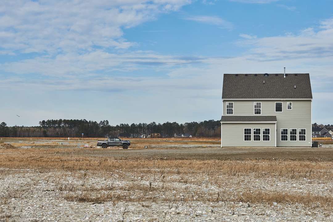 белый и черный дом на коричневом поле под голубым небом пазл онлайн