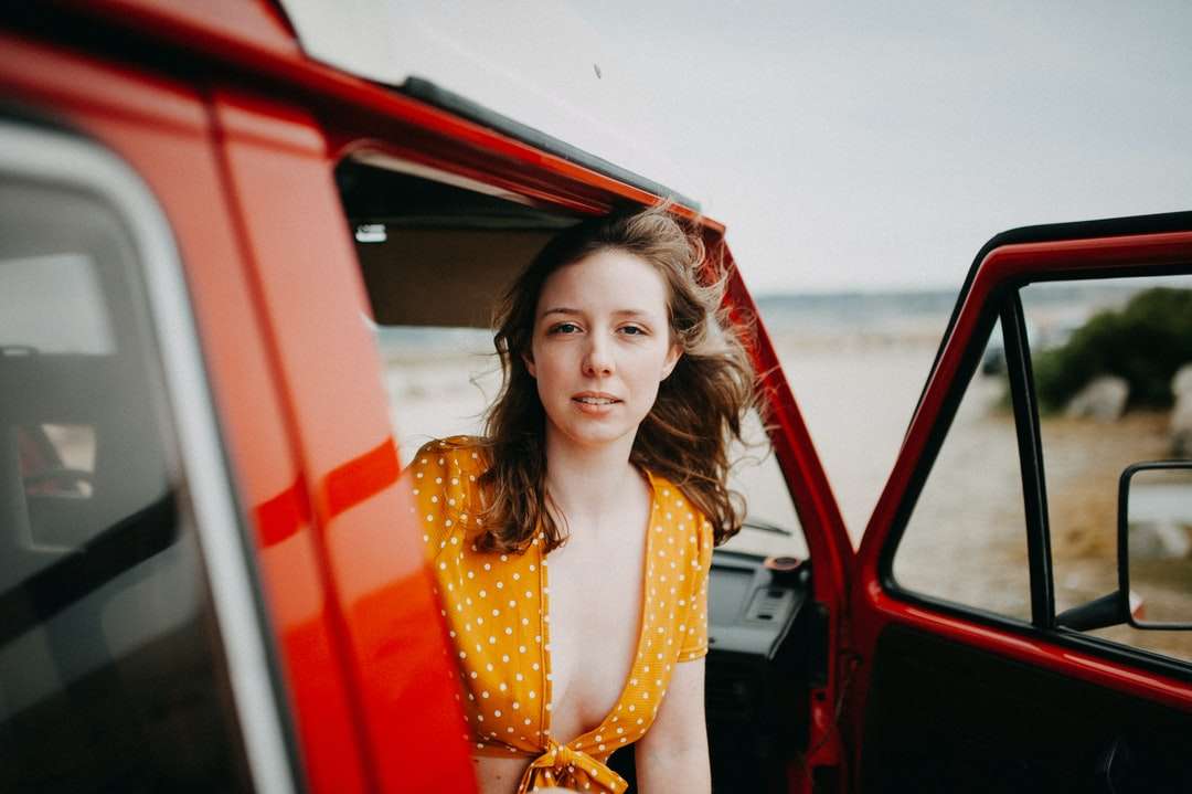Femme en robe sans manches jaune debout à côté de voiture rouge puzzle en ligne