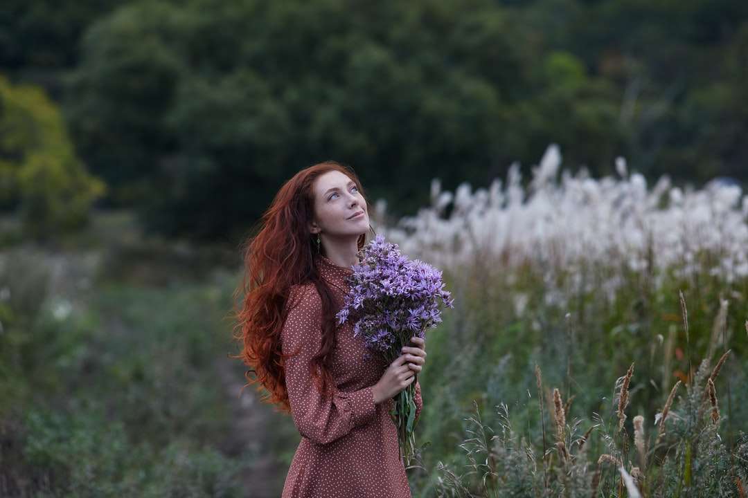 Frau im braunen Pullover, der lila Blumen hält Online-Puzzle