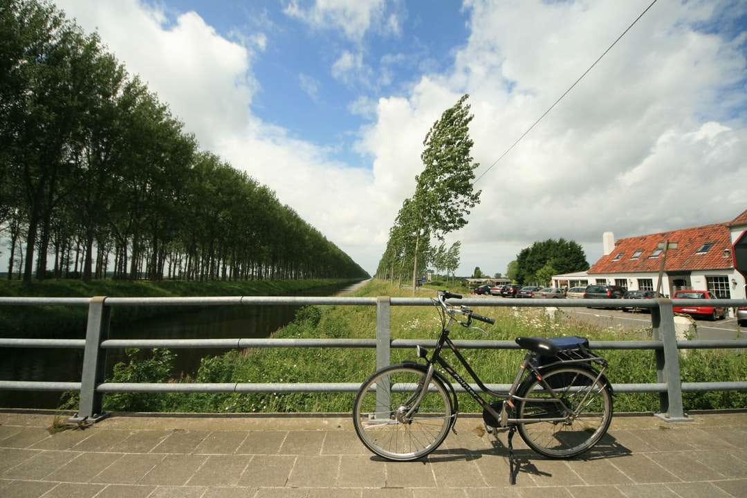 Bicicleta negra estacionada junto a la valla metálica verde rompecabezas en línea