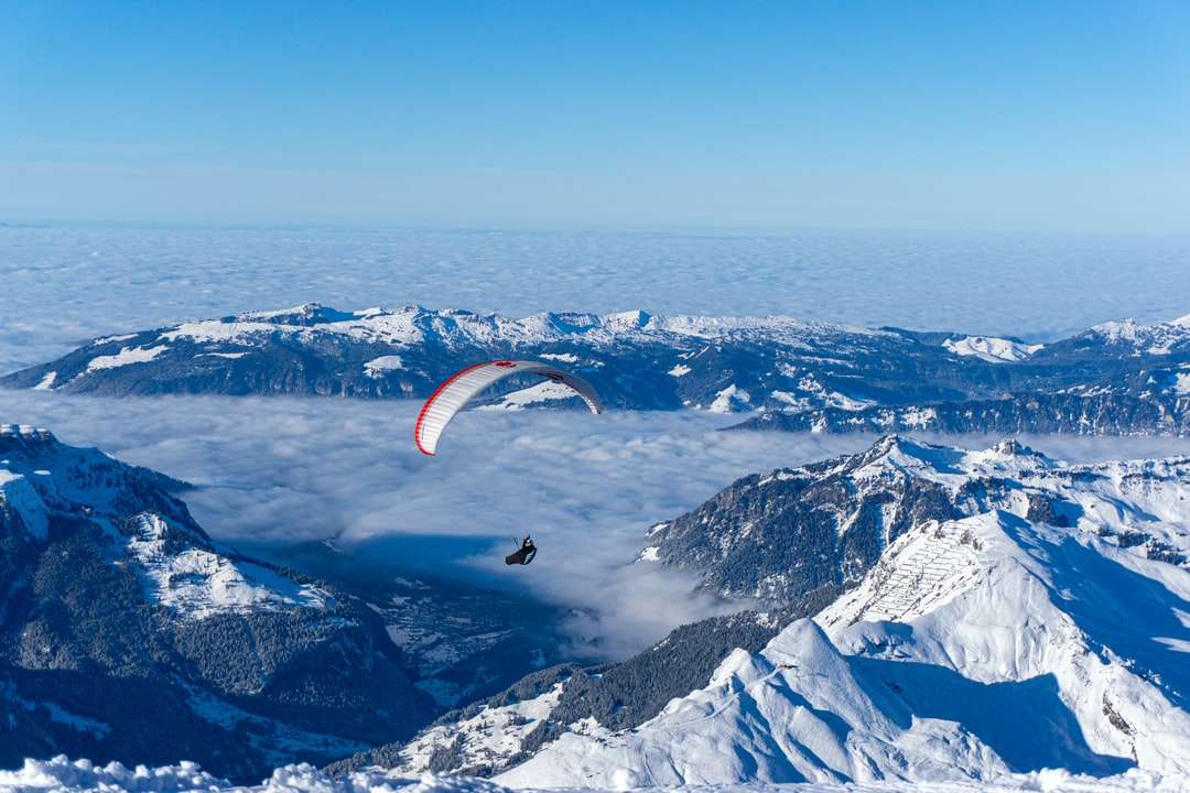 Persona montada en paracaídas sobre montañas cubiertas de nieve rompecabezas en línea