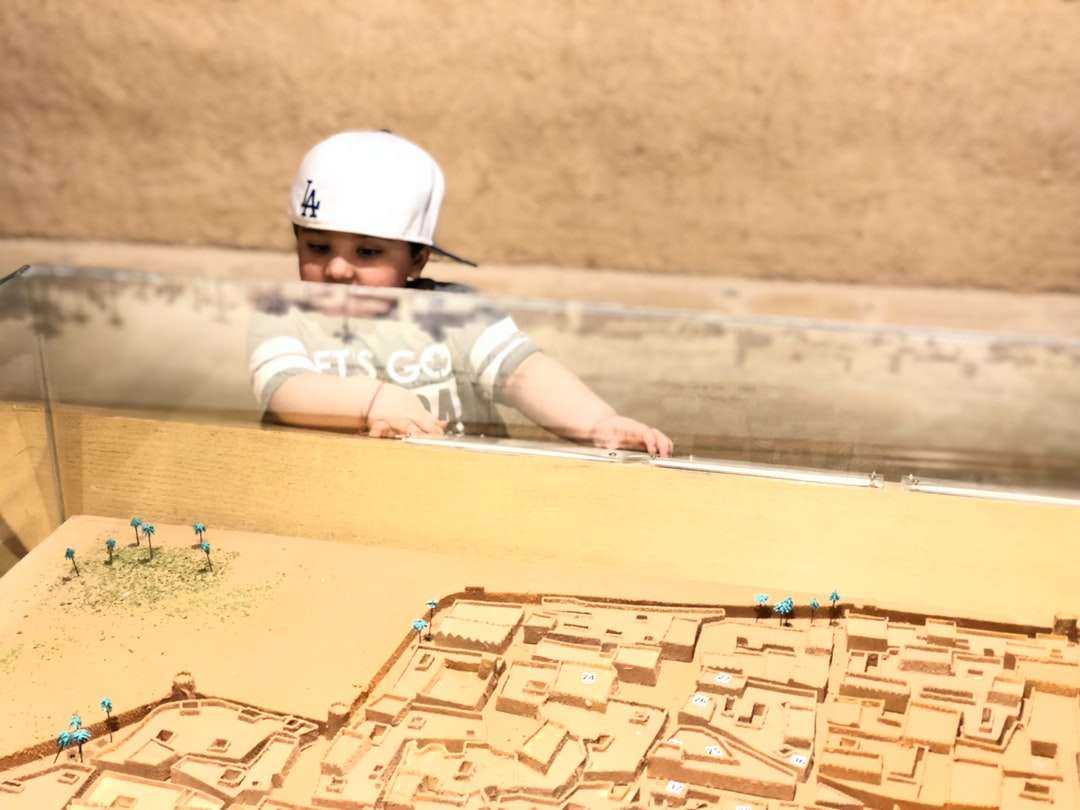 dítě v bílé helmě ležící na hnědém písku během dne online puzzle