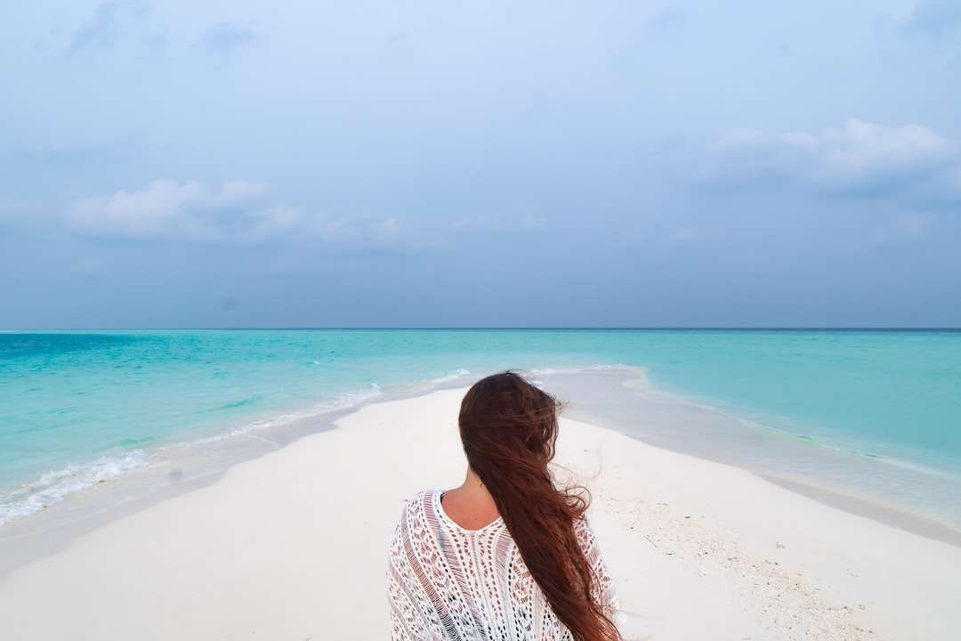 mulher de camisa branca e preta de bolinhas em pé na praia quebra-cabeças online