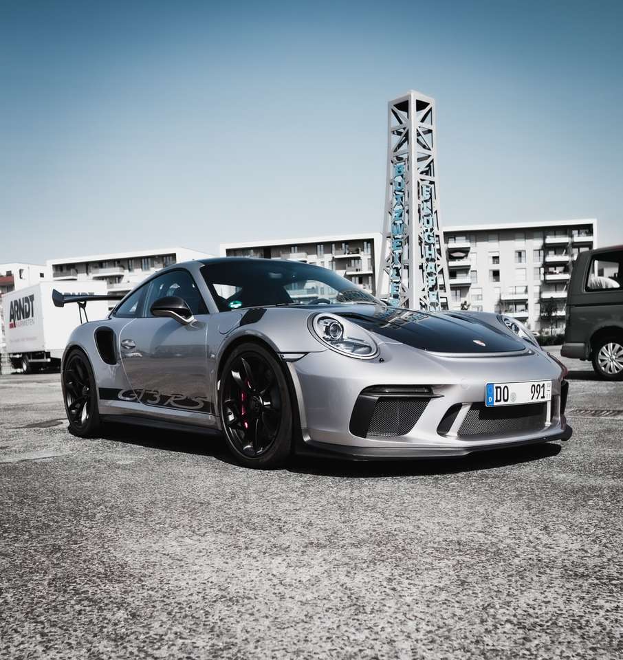blau-weißer Porsche 911 auf grauem Betonpflaster geparkt Puzzlespiel online