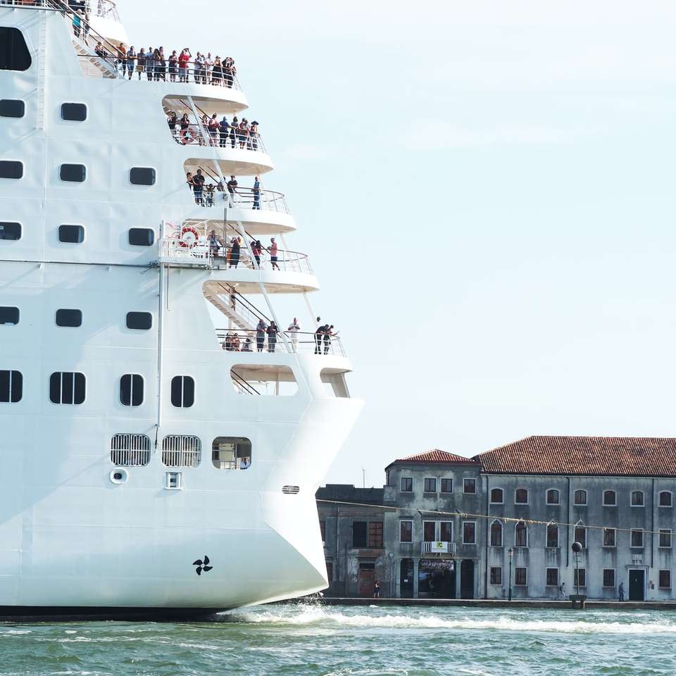 bílá loď na vodní hladině poblíž hnědé betonové budovy online puzzle