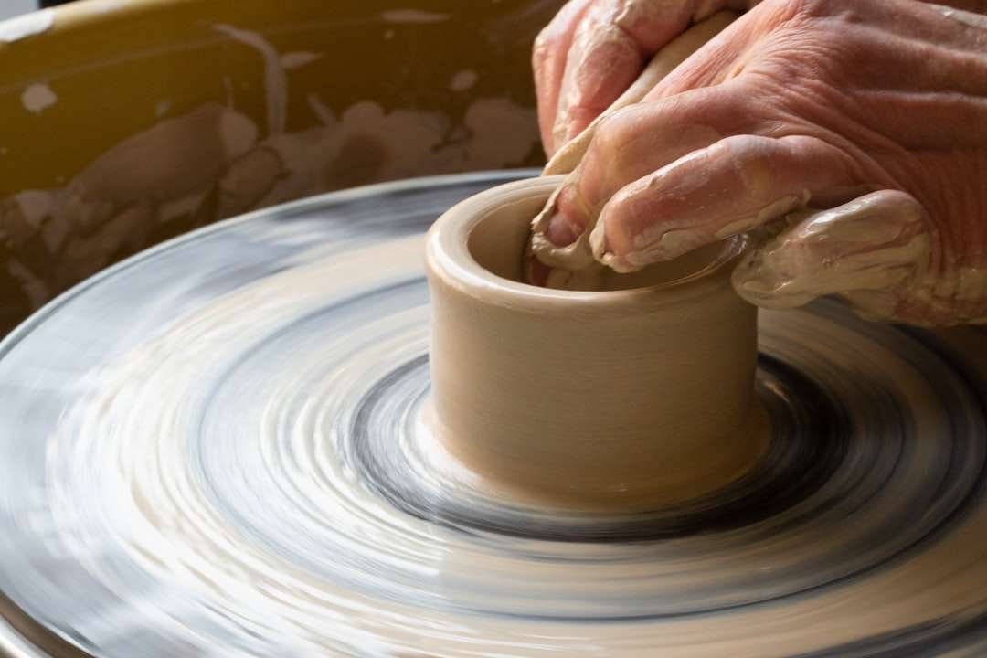 person making clay pot on white round plate jigsaw puzzle online