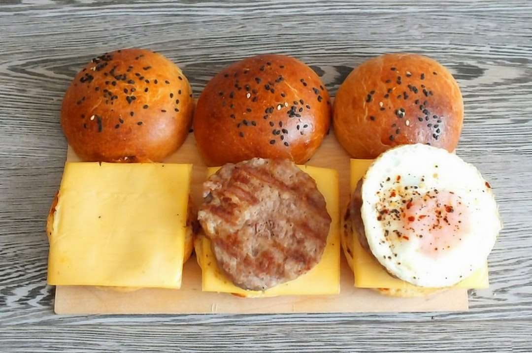 Dos hamburguesas con queso y huevo en placa de cerámica blanca rompecabezas en línea