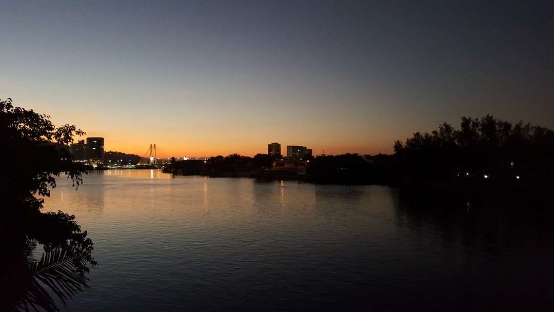 Schattenbild von Gebäuden nahe dem Gewässer während des Sonnenuntergangs Puzzlespiel online
