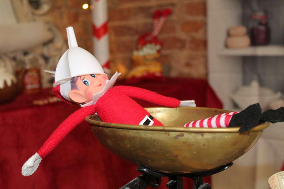 дитина в червоно-білий Санта капелюх на коричневий дерев'яну миску пазл онлайн