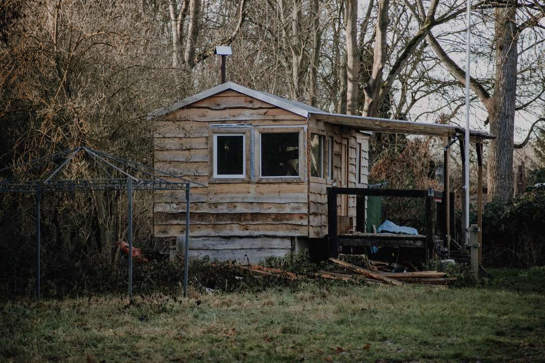 коричневый деревянный дом возле деревьев в дневное время пазл онлайн