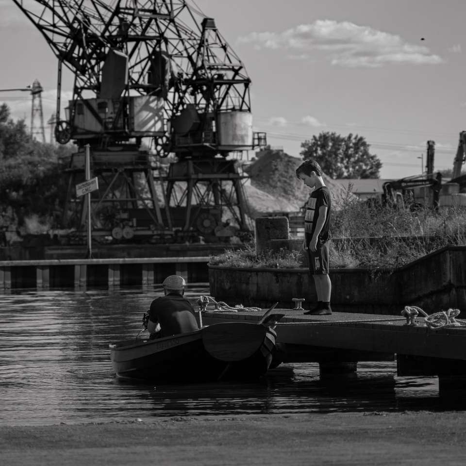 Foto en escala de grises del hombre montado en un barco rompecabezas en línea