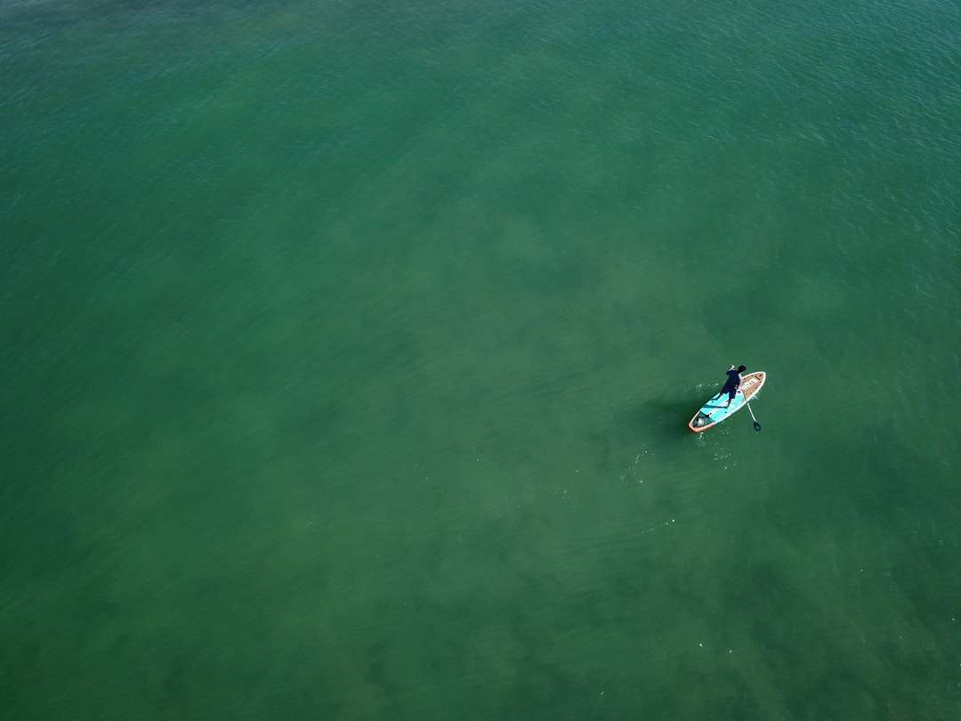 pessoa surfando no mar verde durante o dia quebra-cabeças online