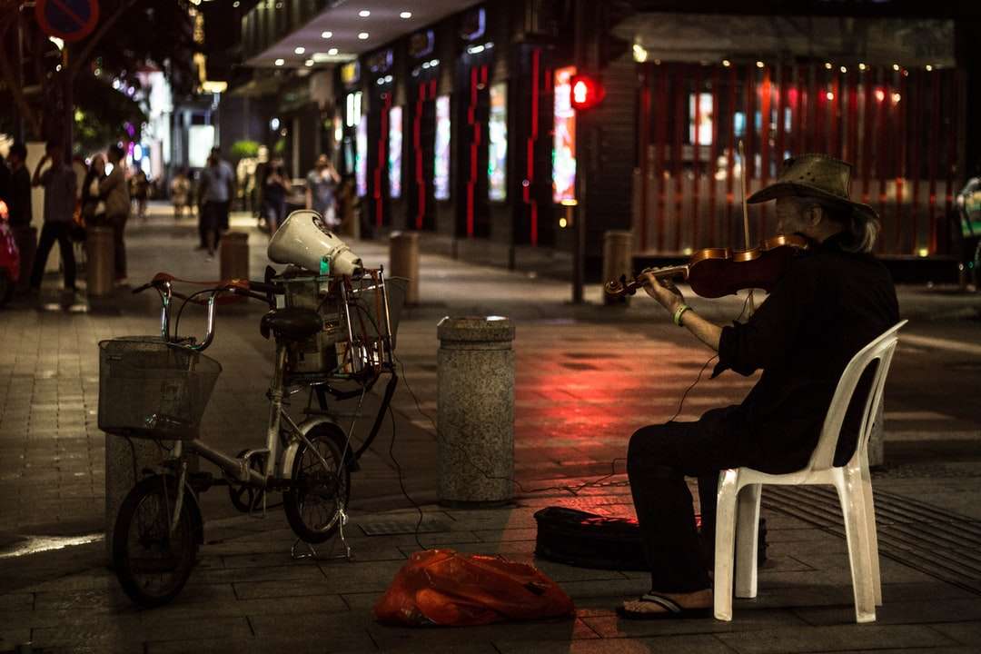 мъж в черна риза, седнал на бял пластмасов стол близо до пътя онлайн пъзел