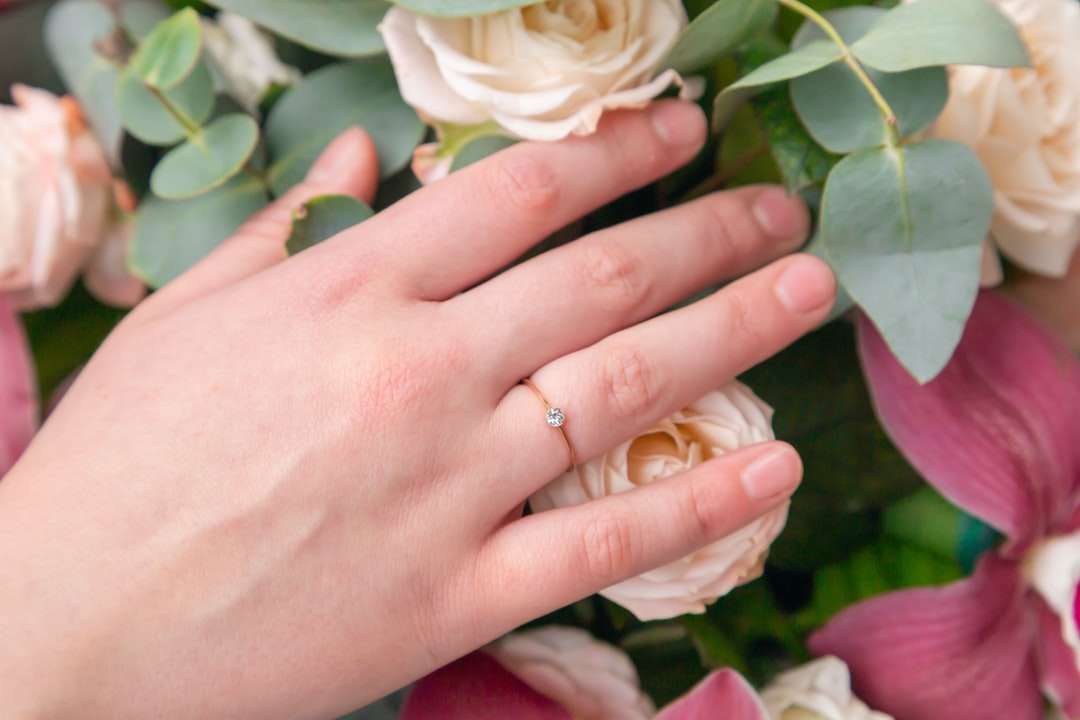 άτομο που φοράει χρυσό γαμήλιο συγκρότημα κρατώντας λευκό τριαντάφυλλο παζλ online