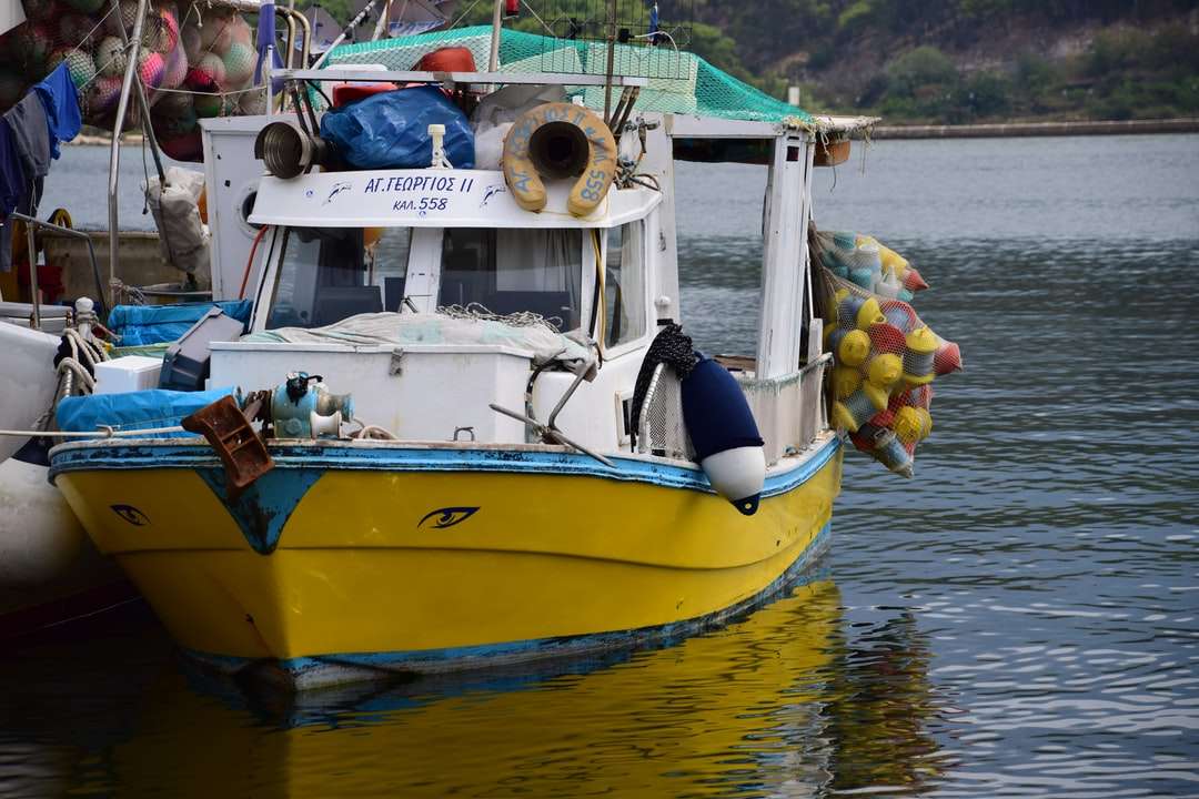 gelbes und blaues Boot auf dem Wasser während des Tages Puzzlespiel online