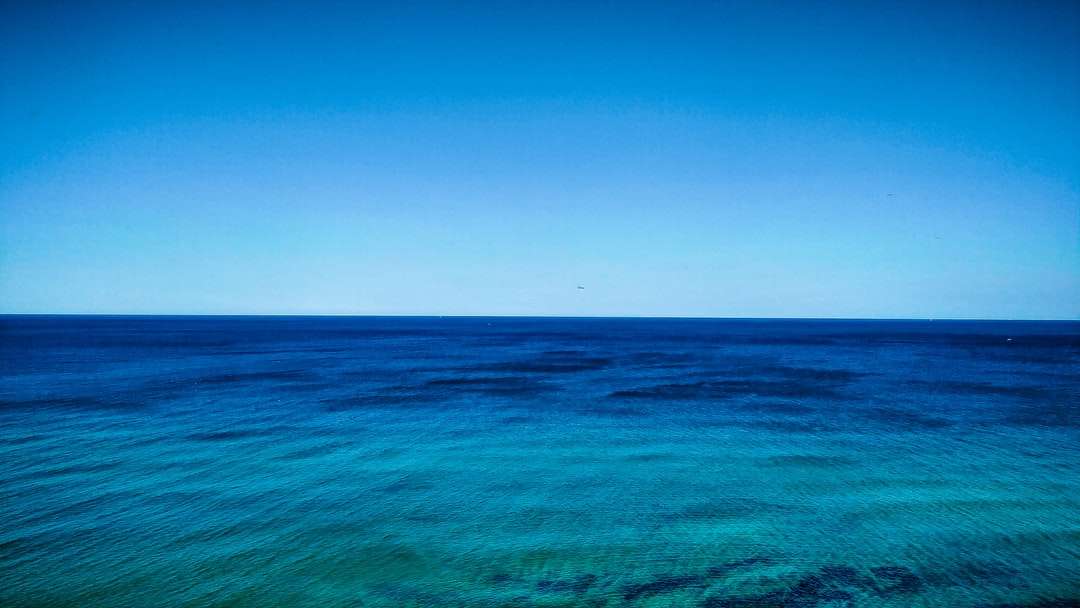 μπλε ωκεανό νερό κάτω από το γαλάζιο του ουρανού κατά τη διάρκεια της ημέρας παζλ online