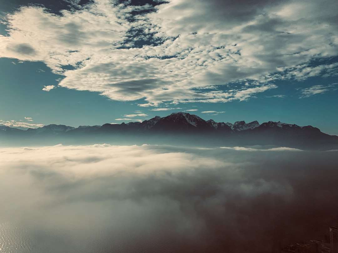 munți sub nori albi și cer albastru în timpul zilei puzzle online