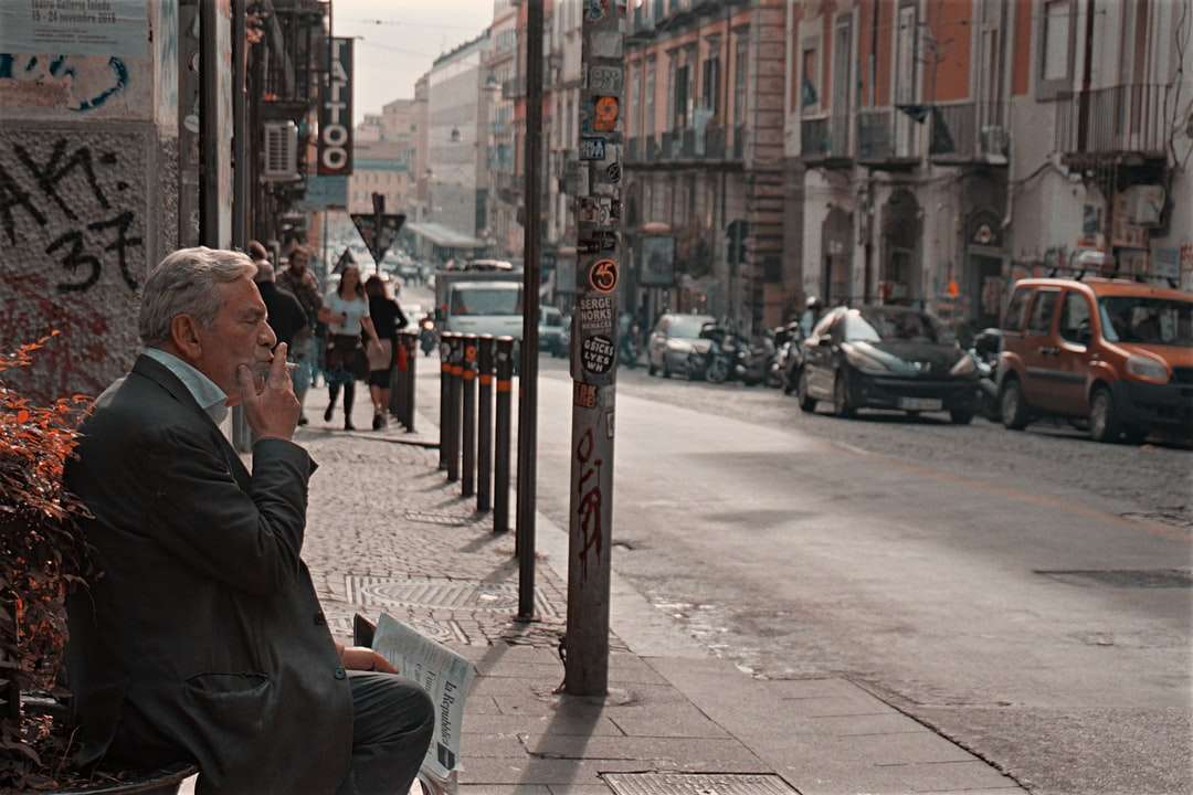 道路の近くのベンチに座っている黒いジャケットの男 オンラインパズル