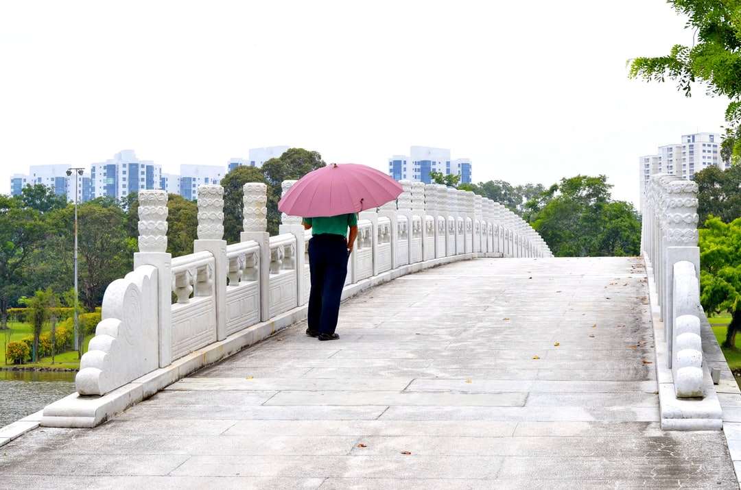 Frau in der schwarzen Hose, die rosa Regenschirm hält Puzzlespiel online