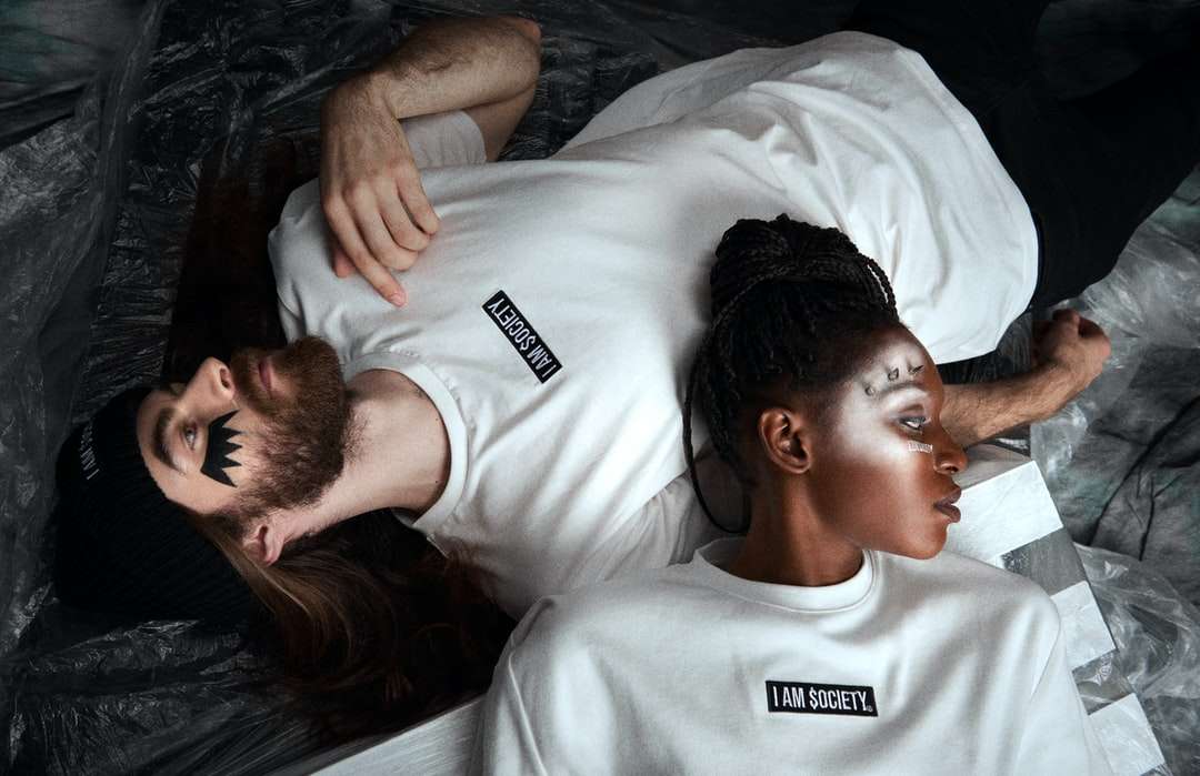 Mann im weißen Rundhalsausschnitt-T-Shirt, das auf schwarzem Textil liegt Online-Puzzle