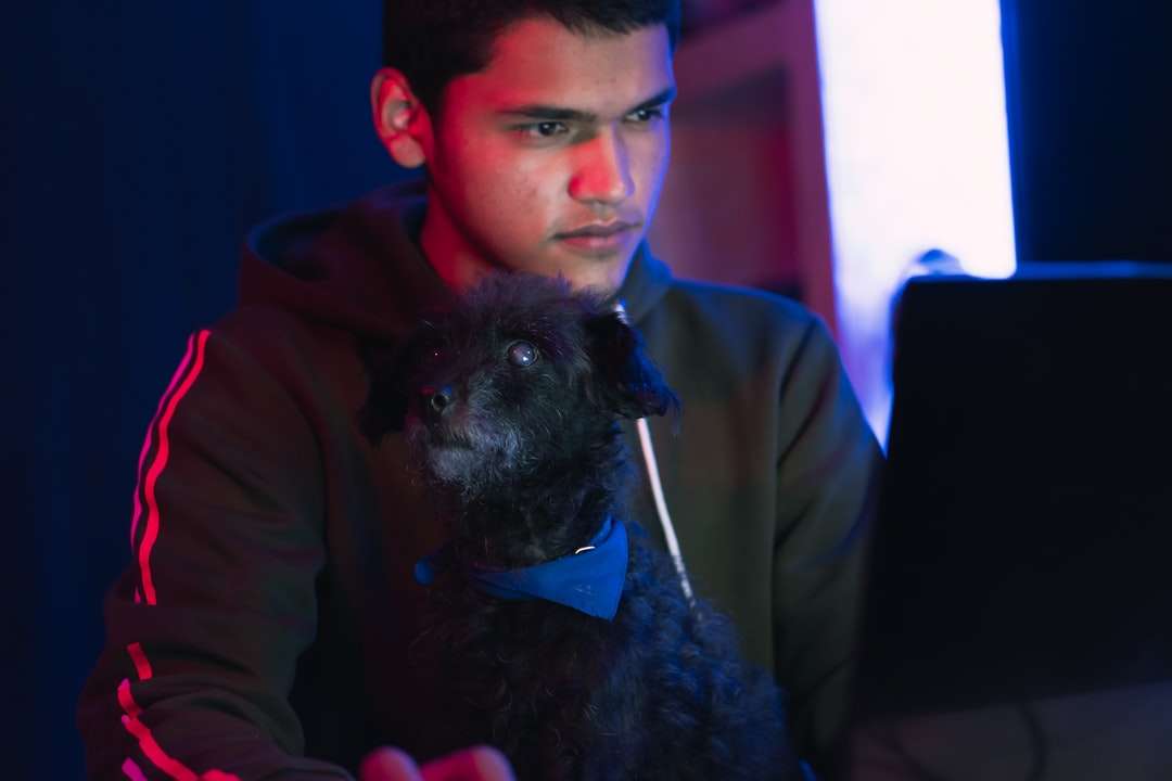homem de casaco marrom segurando um cachorro pequeno de casaco longo preto quebra-cabeças online