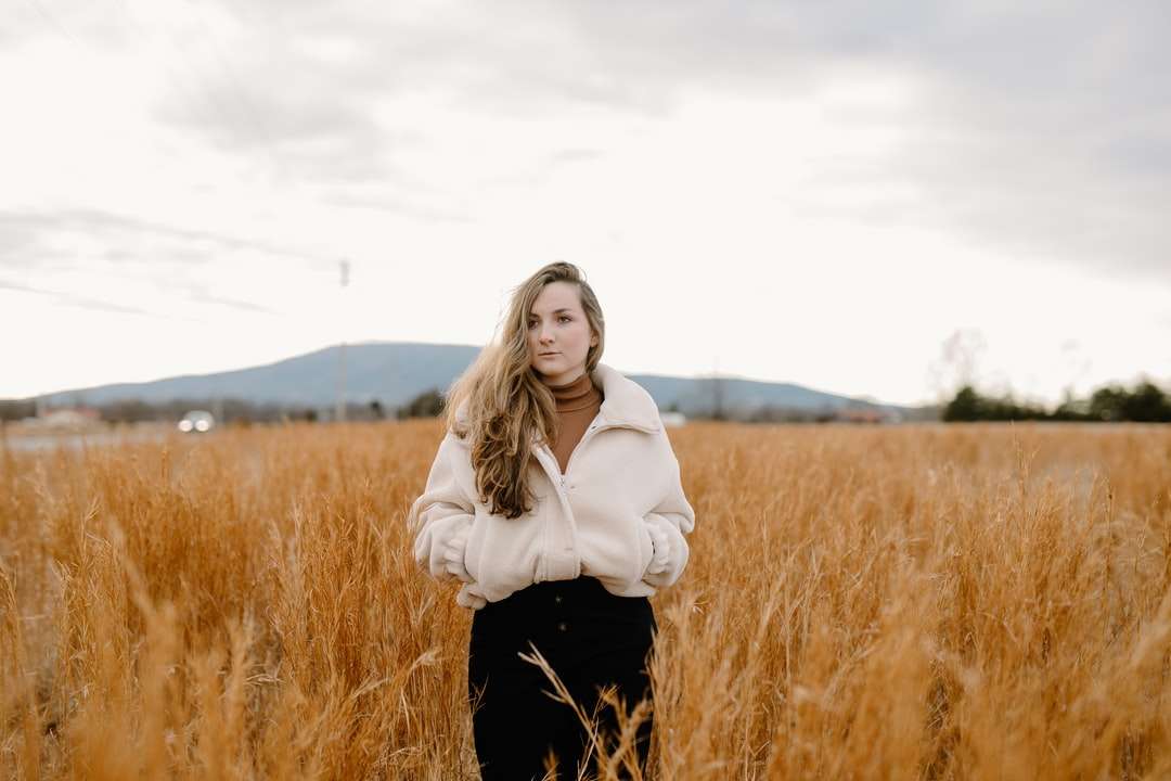 mulher de jaqueta branca em pé no campo de grama marrom puzzle online