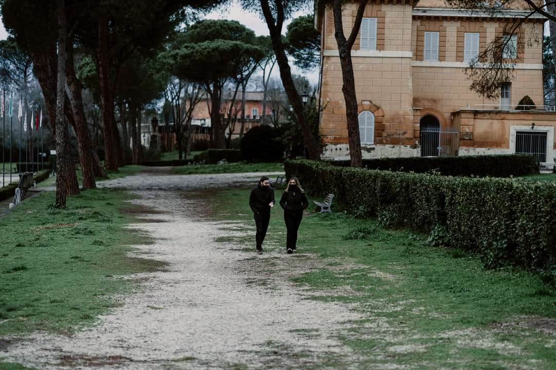 pessoa de jaqueta preta caminhando em um caminho de concreto cinza quebra-cabeças online