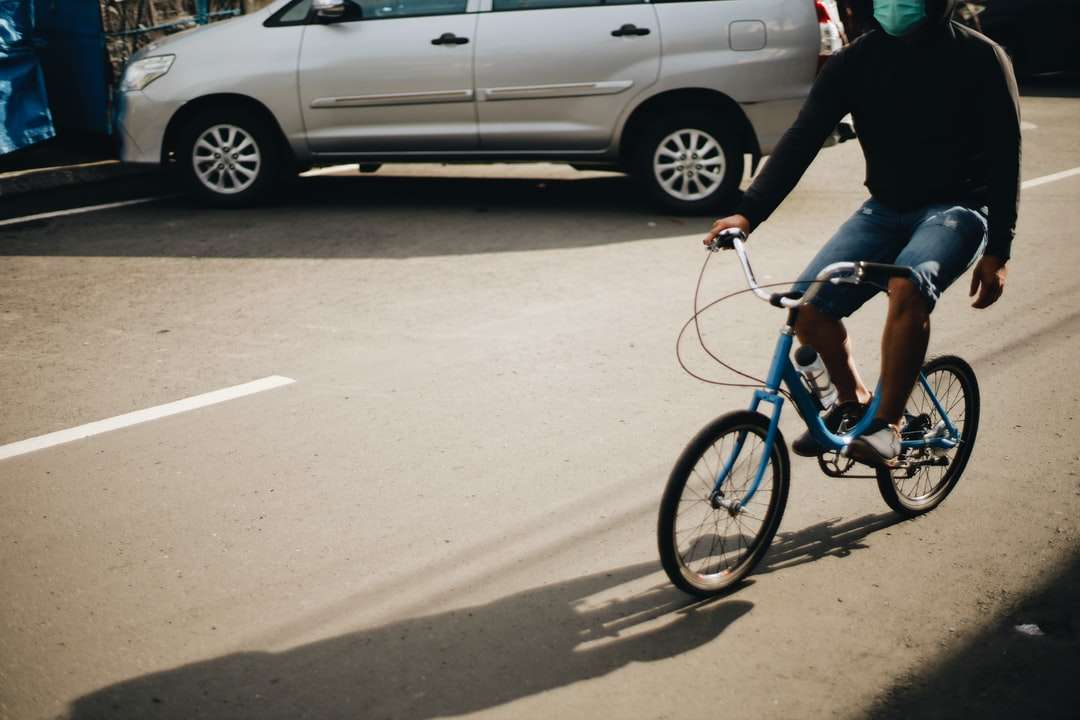 Mann in der schwarzen Jacke, die tagsüber auf blauem Fahrrad reitet Online-Puzzle