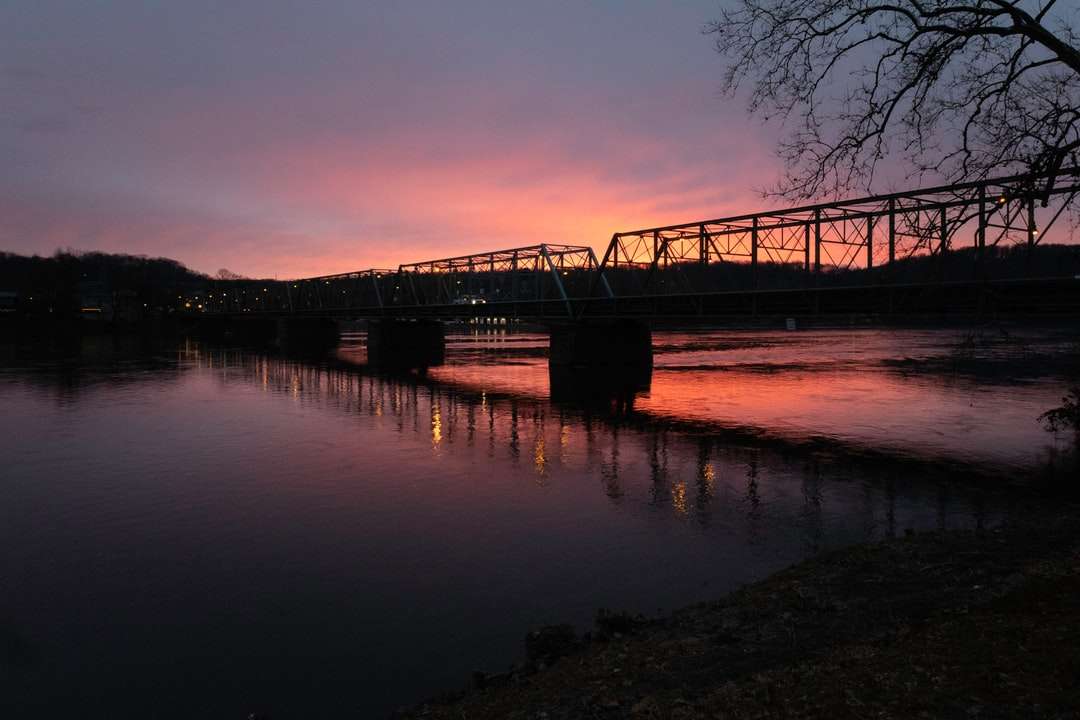silhueta da ponte sobre a água durante o pôr do sol quebra-cabeças online