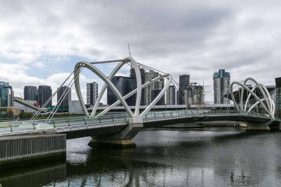 witte brug over de rivier onder bewolkte hemel overdag online puzzel