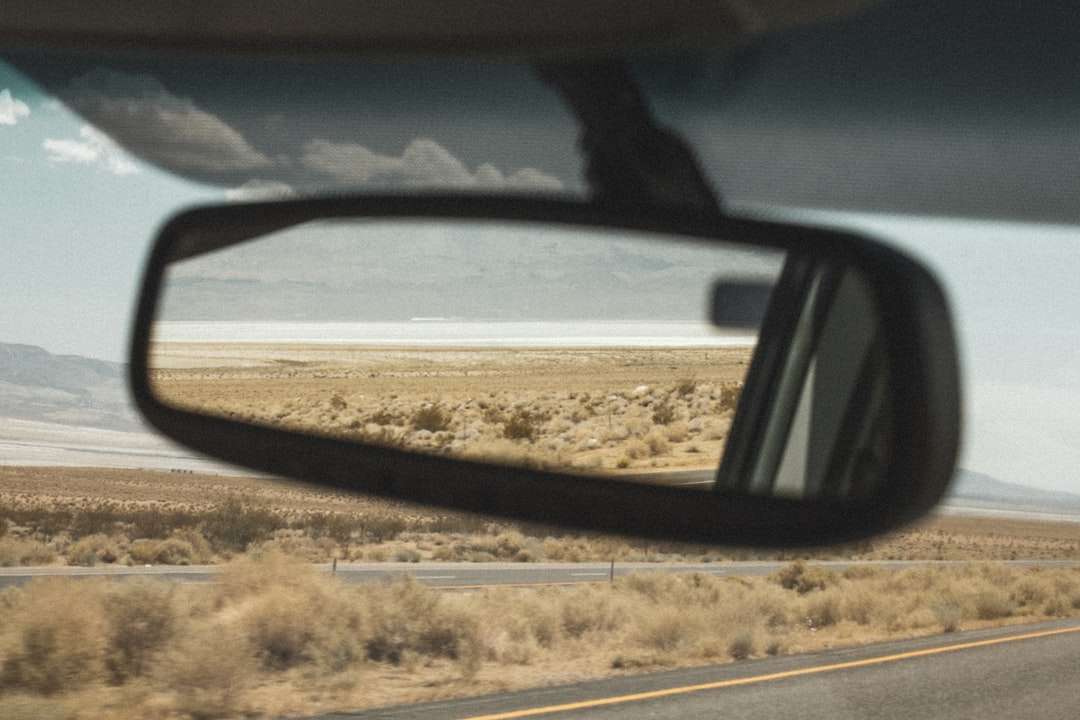 black car side mirror reflecting brown field during daytime online puzzle