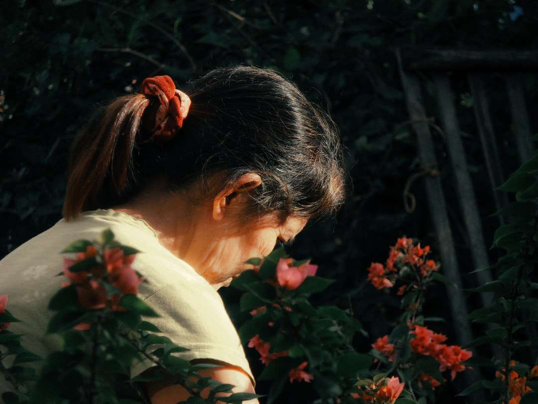 жінка в білій сорочці стоїть біля зелених рослин пазл онлайн