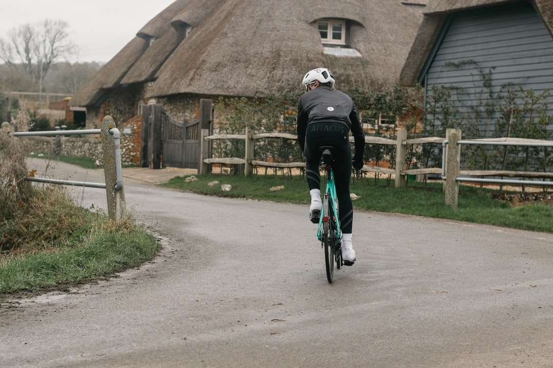 om în jachetă neagră călare pe bicicletă pe un drum de beton gri jigsaw puzzle online