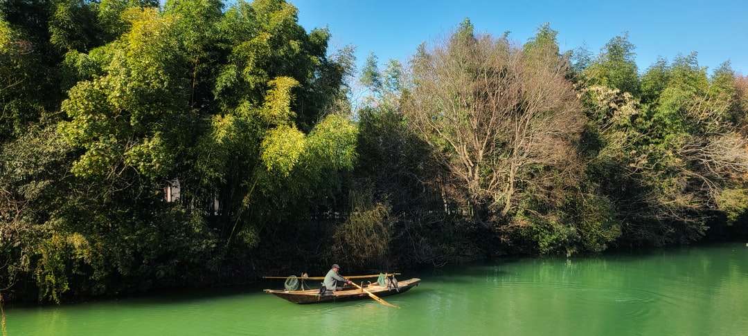 緑の木々に囲まれた緑の湖の白いボート オンラインパズル