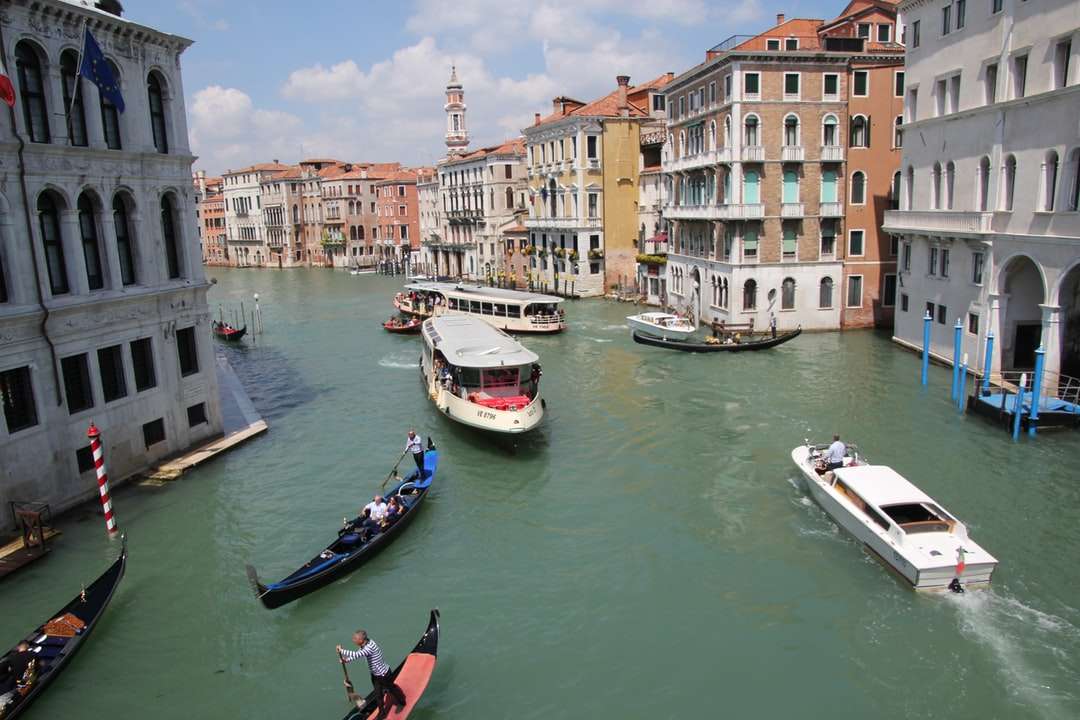 witte en blauwe boot op rivier in de buurt van gebouwen overdag legpuzzel online
