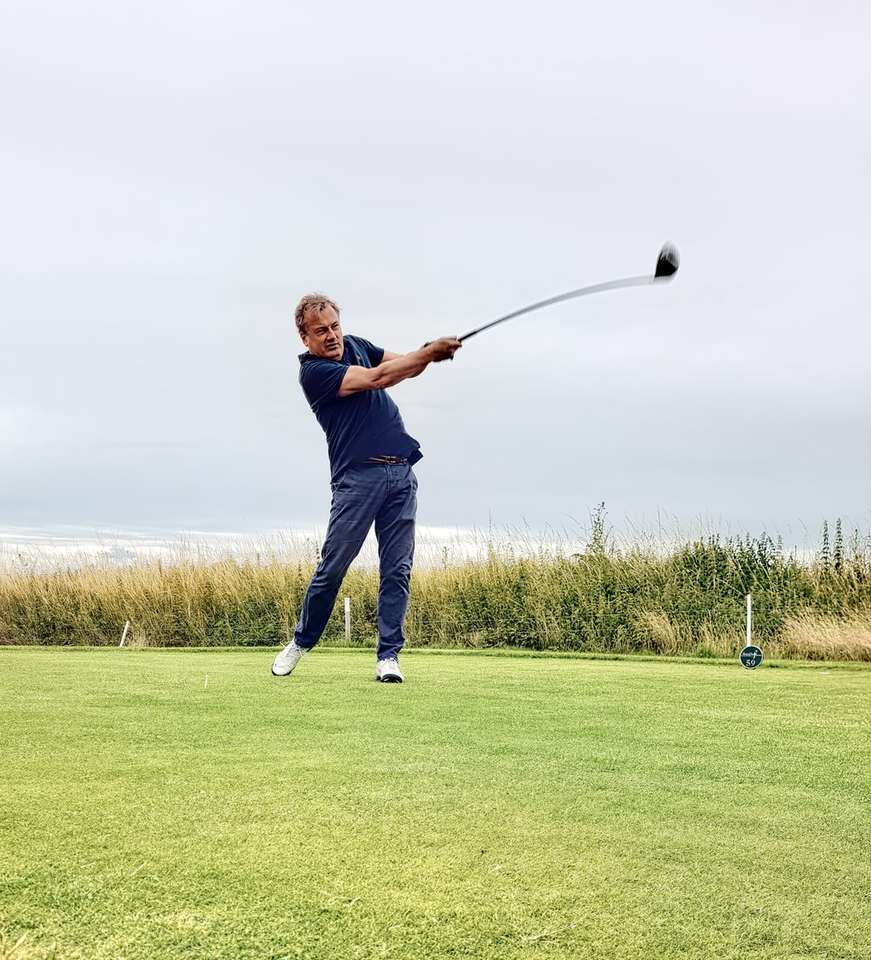 мъж в черно яке и сини дънкови дънки, държащ голф клуб онлайн пъзел