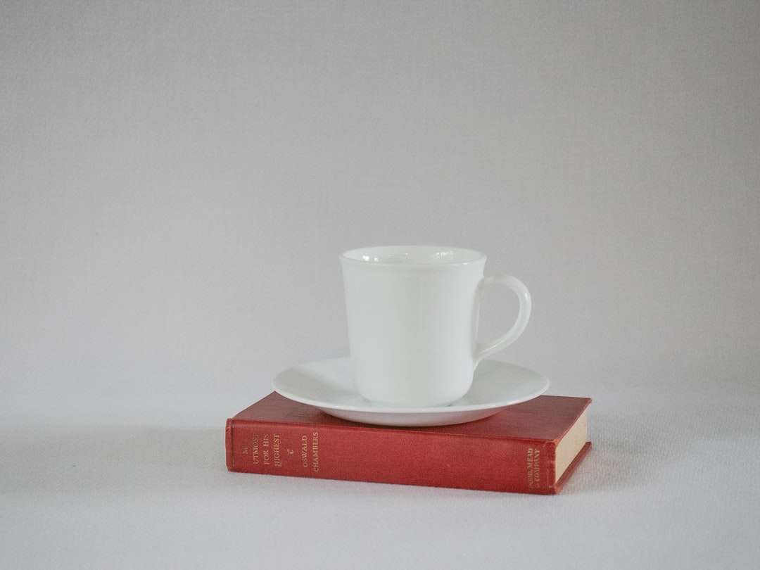 Taza de cerámica blanca sobre libro rojo rompecabezas en línea