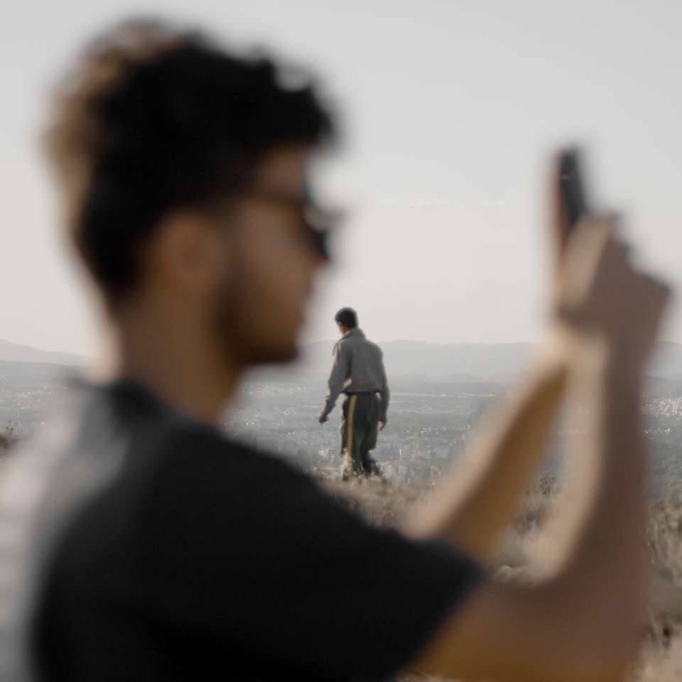 άντρας σε μαύρο πουκάμισο κρατώντας smartphone online παζλ