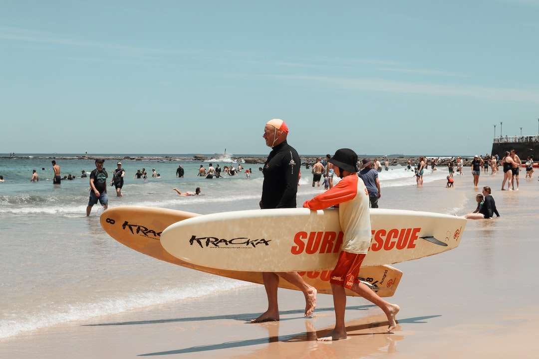 Hombre en traje de neopreno negro con tabla de surf blanca rompecabezas en línea