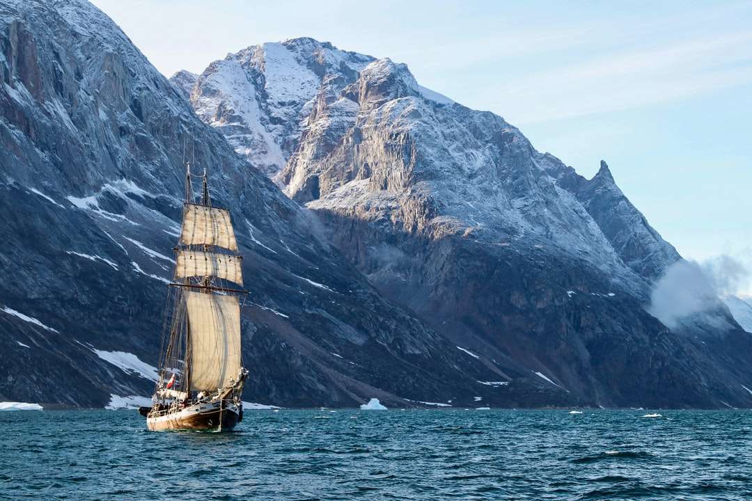 кафява и бяла лодка в морето близо до планината през деня онлайн пъзел