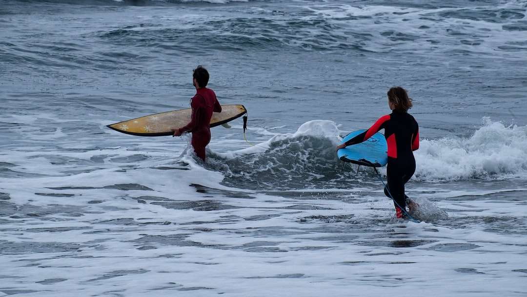 homem de terno vermelho e preto segurando uma prancha de surf branca quebra-cabeças online