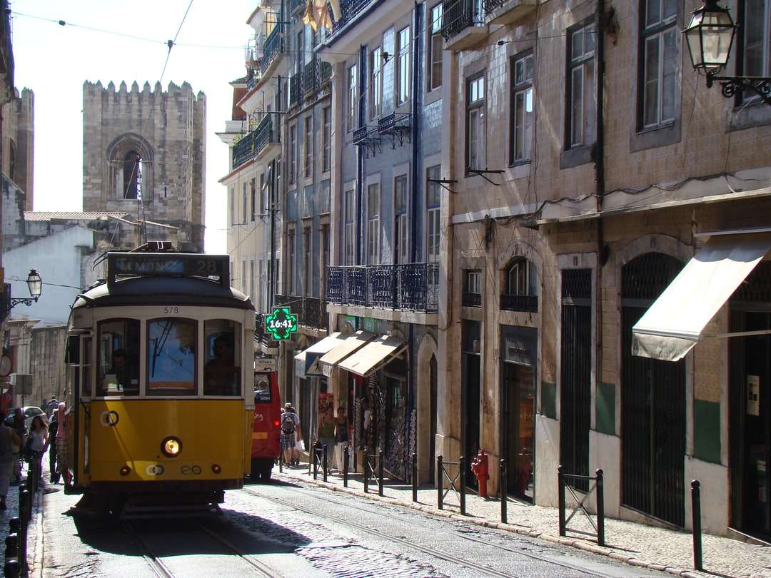 gelbe und rote Straßenbahn auf der Straße in der Nähe des Gebäudes während des Tages Puzzlespiel online