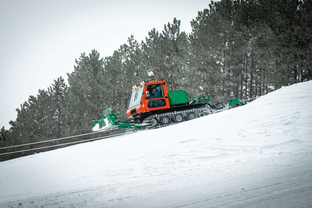Tractor verde y naranja sobre suelo cubierto de nieve rompecabezas en línea