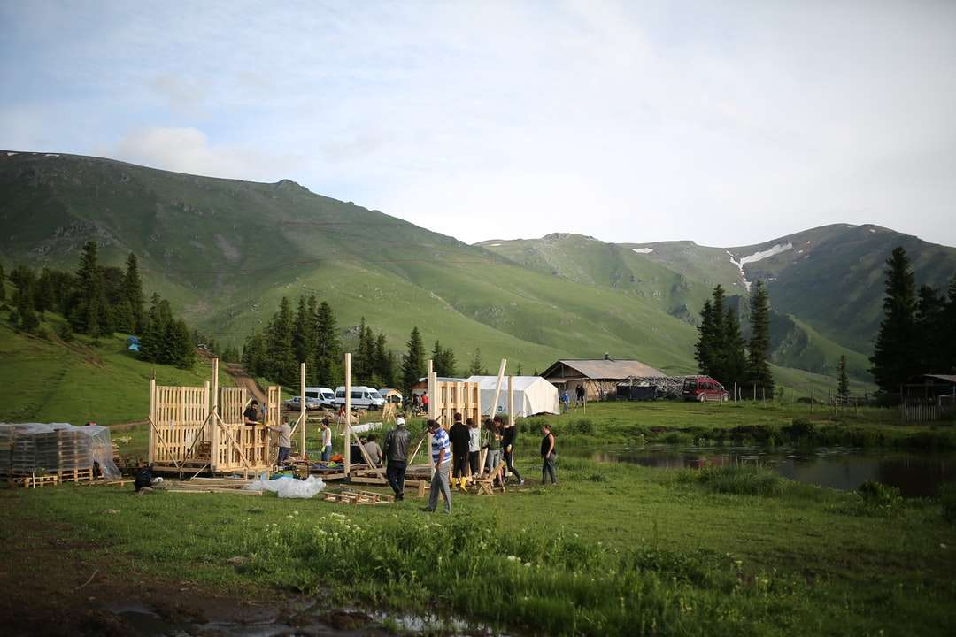 хора, стоящи на поле със зелена трева близо до зелени планини онлайн пъзел