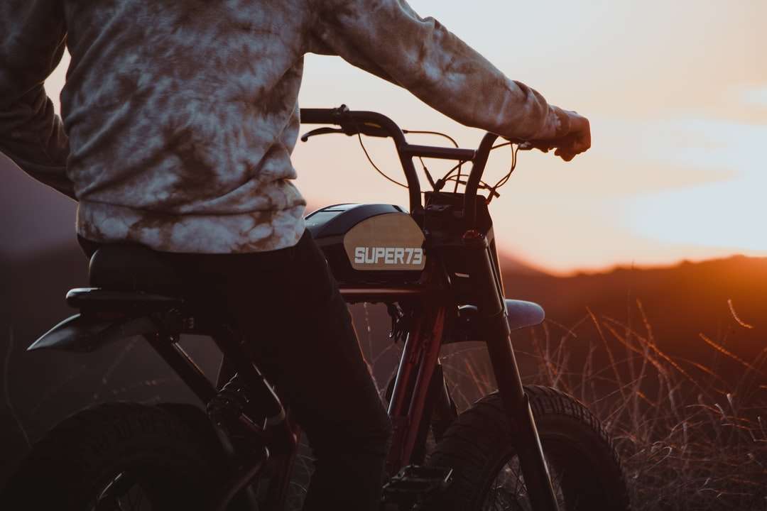 άτομο σε γκρι σακάκι ιππασίας μαύρη μοτοσικλέτα κατά το ηλιοβασίλεμα online παζλ