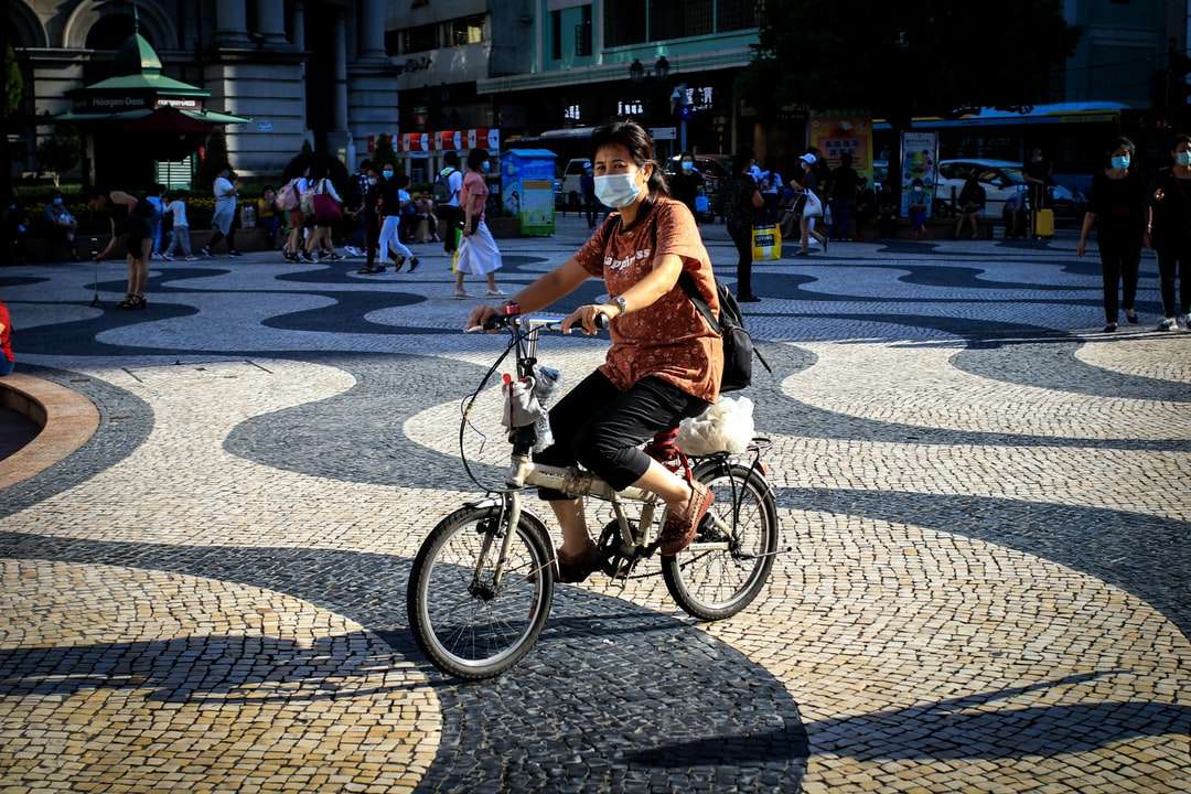 женщина в коричневой рубашке едет на велосипеде по дороге онлайн-пазл