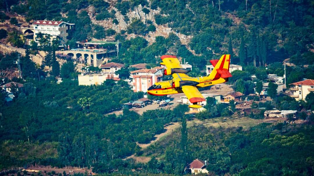 gelbes und rotes Flugzeug, das über grünes Grasfeld fliegt Online-Puzzle