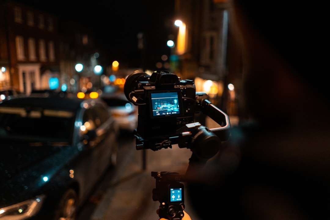 человек держит черную камеру dslr, фотографируя улицу пазл онлайн
