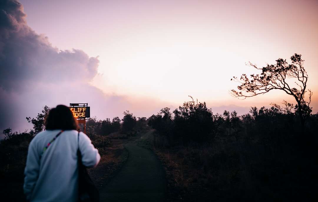 Hombre con camisa blanca de pie en la carretera durante la puesta de sol rompecabezas en línea